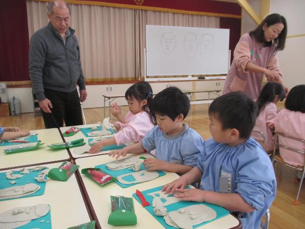 写真：顔のお面を油粘土で作っている園児たち