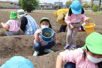 写真：取れた草を見せる子ども