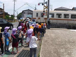 写真：踏切で電車を見送る園児