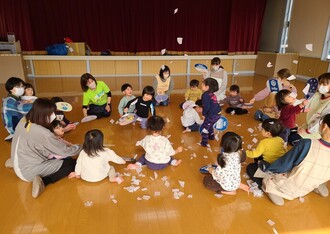 小さく切った白い紙を雪に見立てて、子ども達と職員でうちわで扇ぎ、舞い上がった紙に大はしゃぎしている写真