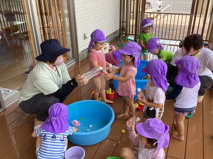 水遊びをしている子どもと保育士