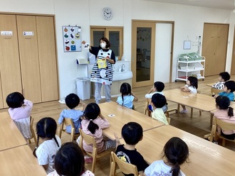 秋の味覚についての話を聞く3歳児の写真