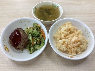 給食の写真（キャロットごはん、きのこハンバーグ、ブロッコリーのおかか和え、わかめと油揚げのみそ汁）