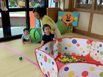 室内のボールプールで楽しく遊ぶ0歳児の写真