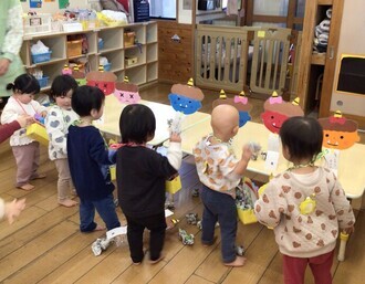 鬼の的に豆をぶつけて節分行事を楽しむ1歳児の写真