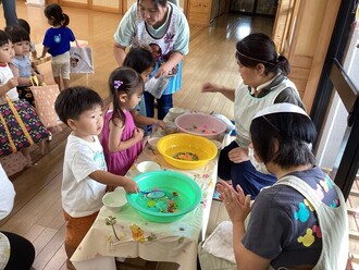 金魚すくいを楽しむ2歳児の写真