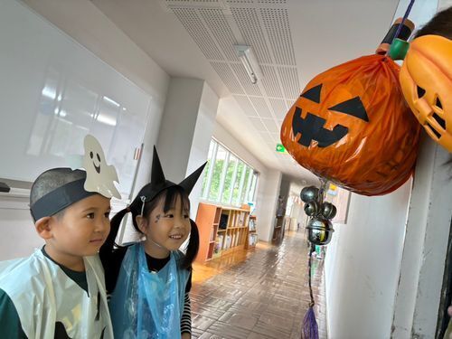 ハロウィンの仮装をしてかぼちゃを見つめるこども二人