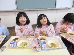 写真：給食体験を喜び、楽しんで食べている女児