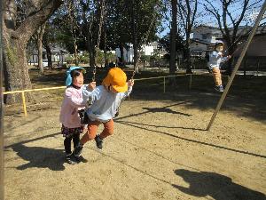 写真：年少さんのブランコ乗りを押してあげる年長女児