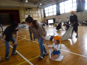 写真：体育館の床をお母さんに引っ張ってもらい楽しむ園児