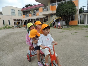 写真：園庭で仲良くなった友達と一緒に自転車乗りをしている様子