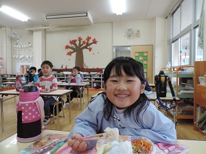 写真：誕生会でみんなでおそろいのお楽しみ弁当を喜んで食べている年長女児