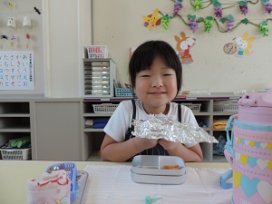 写真：おにぎりを笑顔で食べている年長女児