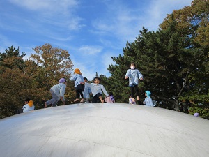 写真：遊具の上で友達と一緒にジャンプを楽しむ幼稚園児の様子