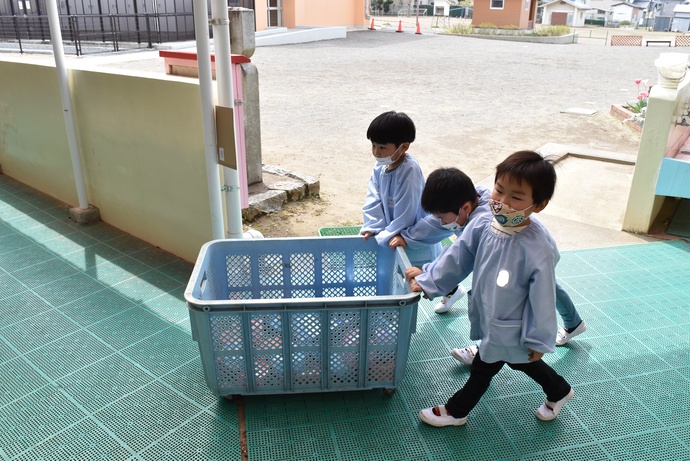 大きなかごに荷物を入れて運ぶ園児