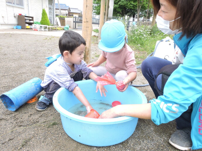 写真 タライの水で遊ぶ幼児