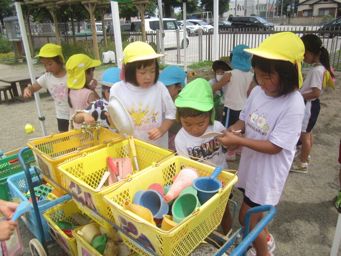 写真 砂場の道具を片づける幼児