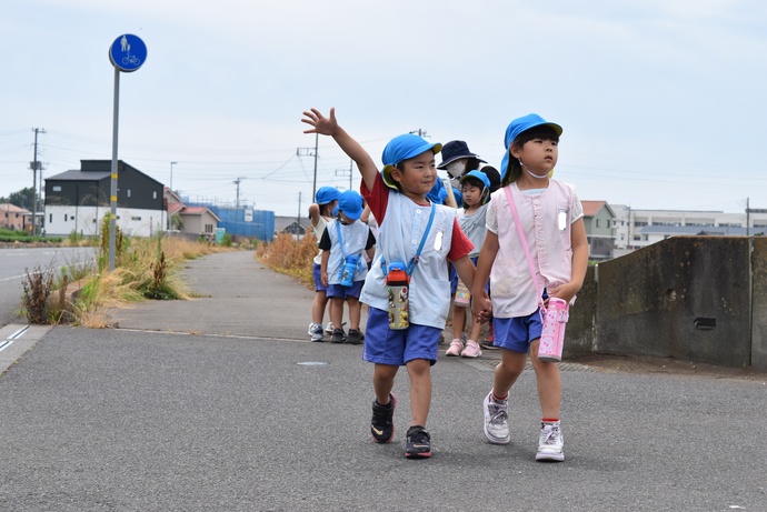 園児が手を上げて道路を渡っている