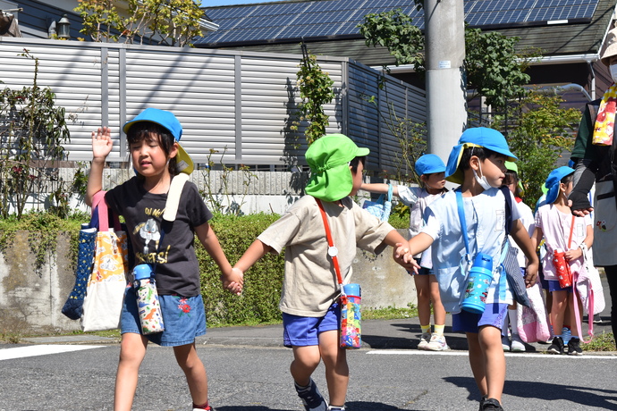 年長児二人が年中児を真ん中にして手をつないで道路を渡っている。