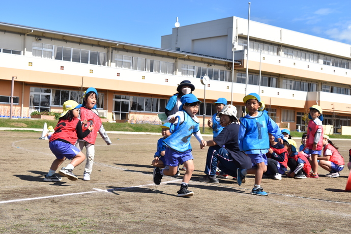 年長さんがリレーのバトンを渡している。