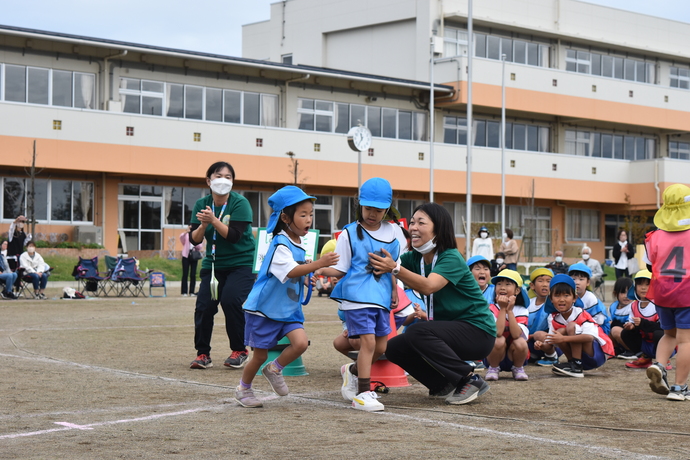 リレーのバトンを渡す幼児と応援する幼児