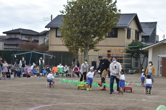 園児と保護者が草に見立てたロープを跳んでいる。