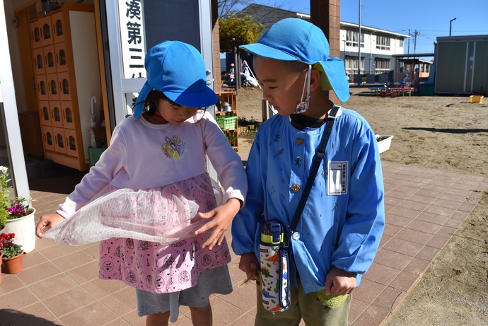 洋服にたくさん着いた種を見る園児