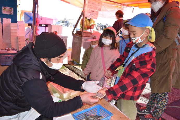 お金を渡して魚を受け取る男の子