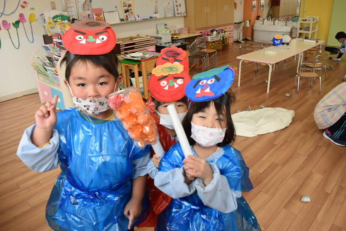 赤と青の鬼のお面をかぶっている3人の園児