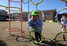 写真 友達の真似をして顔を出す幼児