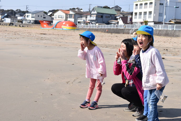 海に向かってヤッホーと呼びかける園児と先生