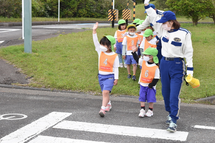 手を上げて、横断歩道を渡る園児と指導員