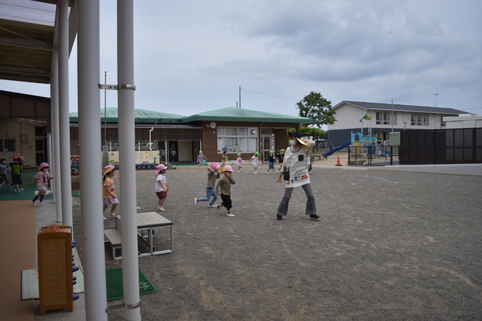 園舎から小走りで園庭に避難する園児たち