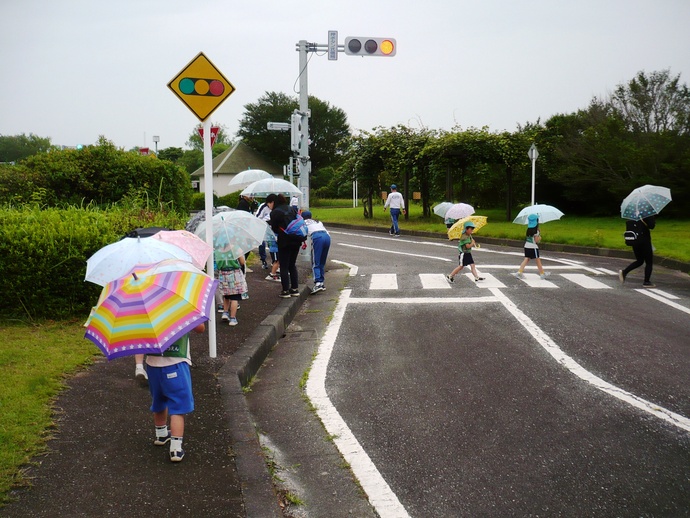 傘をさしながら安全に歩道を歩き、道路を横断する写真