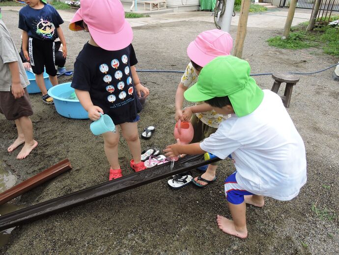 子供たちが水を樋に流す写真