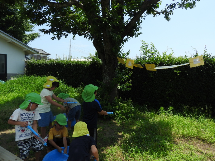 水鉄砲で的当てをする園児