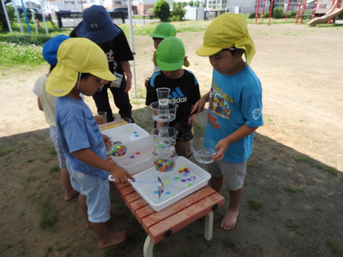 透明カップのタワーに水を流して遊ぶ園児