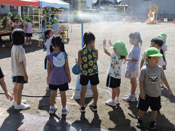 ミストに集まって冷をとる子供たちの写真