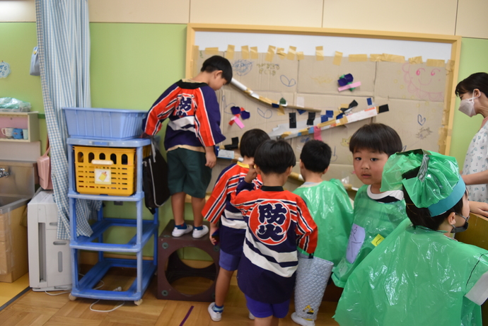 ビー玉を転がす遊びをする園児