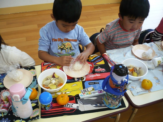 おいしそうな芋煮と幼稚園で取れたお米が混じったおにぎりの写真