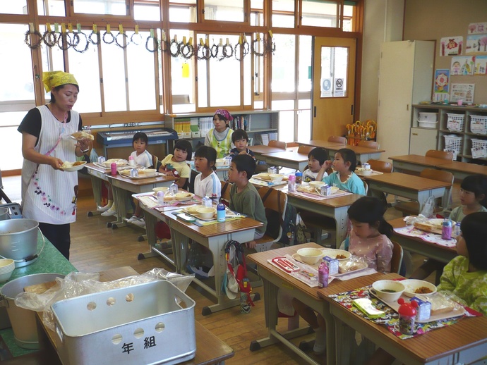 給食の配膳がすみ頂きますを待っている写真