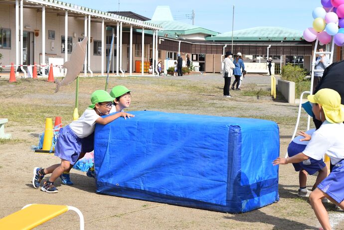 大きなマットを運ぶ園児