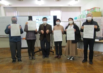 参加者が、自身のやりたい活動の計画を書いたワークシートを持ち、講師を真ん中にして一列で立っている写真