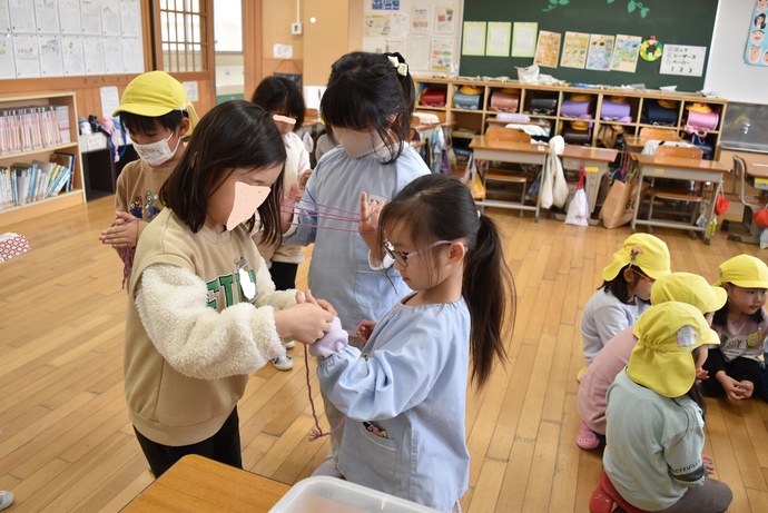 あやとりを教える小学生と園児