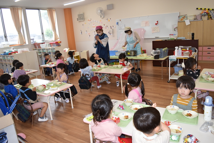 給食が乗ったテーブルを囲む園児たち