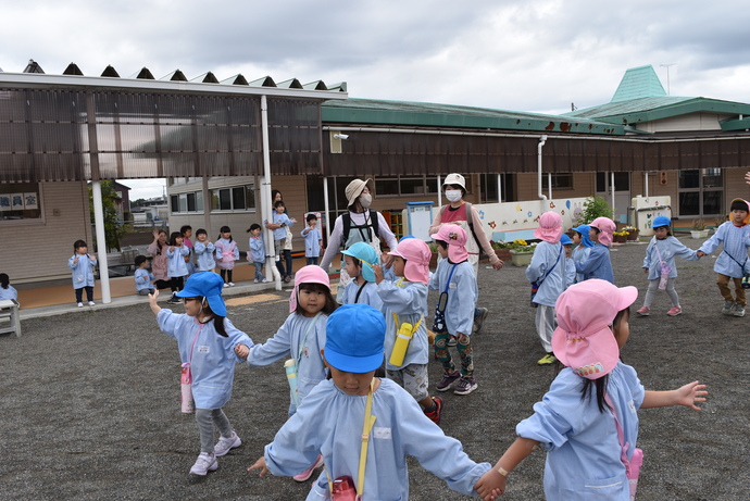 手をつないで歩く園児達と、見送る園児達