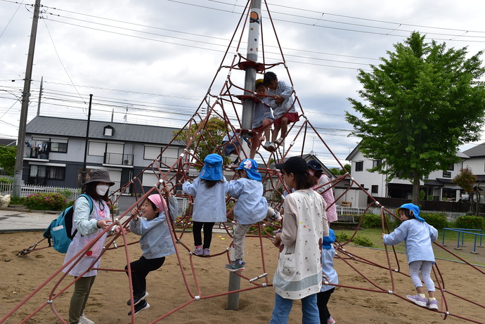 三角形のワイヤージャングルジムに登る園児達