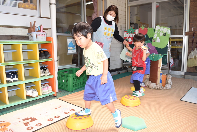 飛び石に見立てた遊具を渡る園児