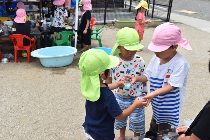 色水の紙コップを持つ園児