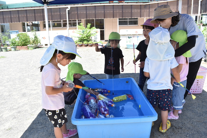 テントの下で魚釣りをする園児たち